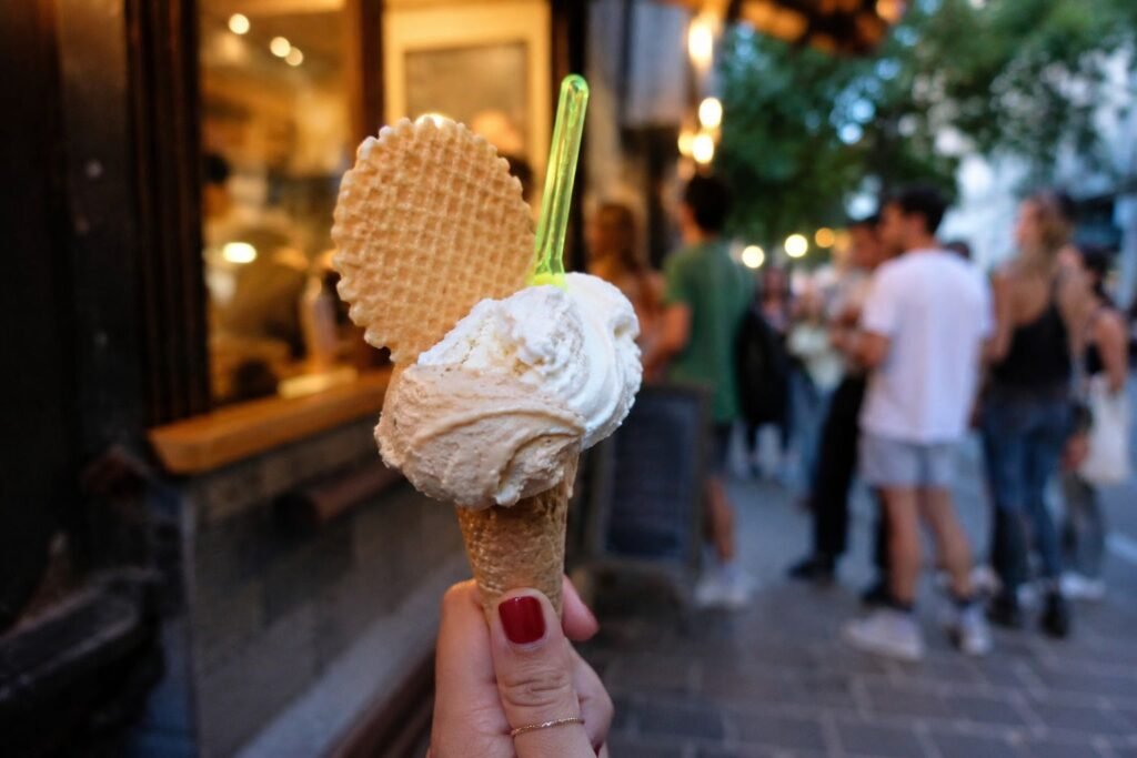 Hand holding a premium gelato cone outside best ice cream shop in NYC during the evening.
