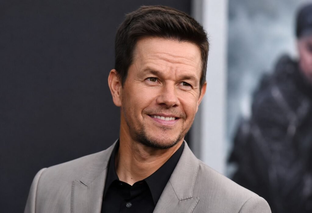 Mark Wahlberg: Career, Net Worth, Movies, and Business Empire Mark Wahlberg smiling at a red carpet event in a light gray jacket and black shirt.